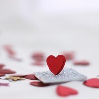 Love hearts scattered on table and one standing up on a piece of silver card
