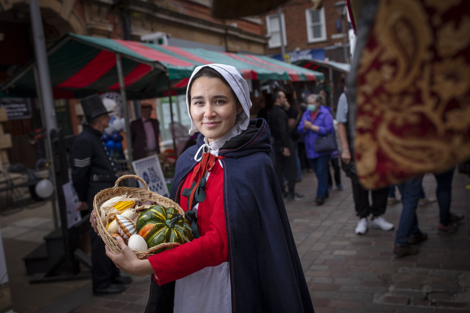 Woman in period costume holding a basket of vegetables at the Merry Olde Market