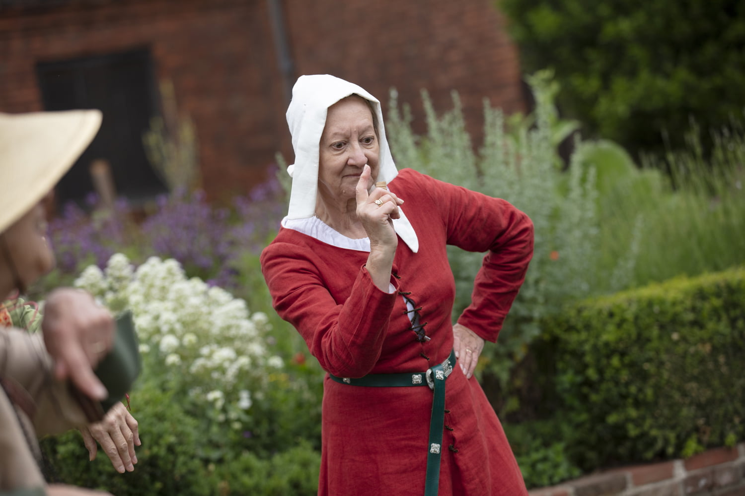 Woman pointing to camera in period costume stood outside Gainsborough Old Hall