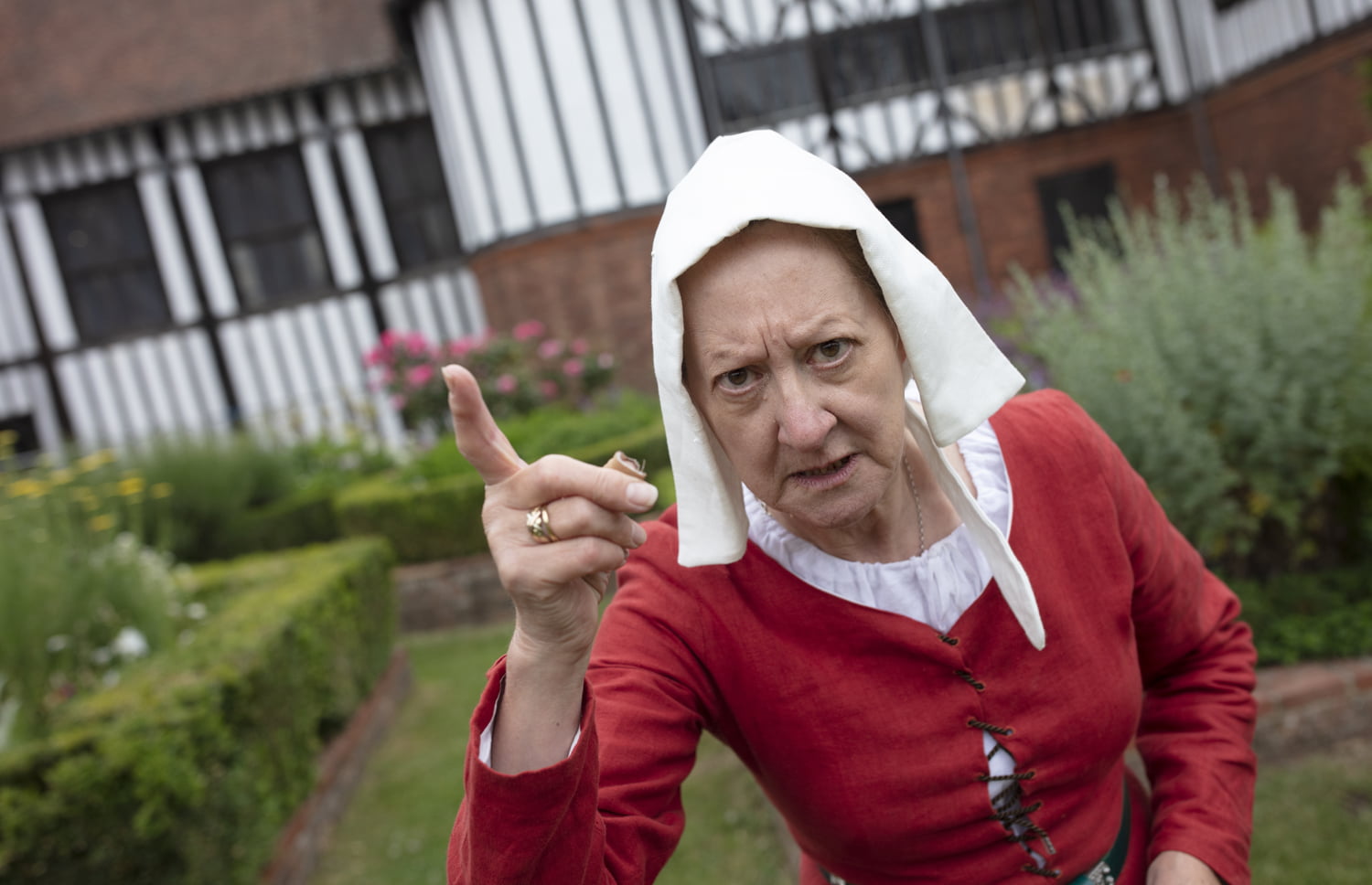 Woman in period costume shaking finger at camera stood outside Gainsborough Old Hall
