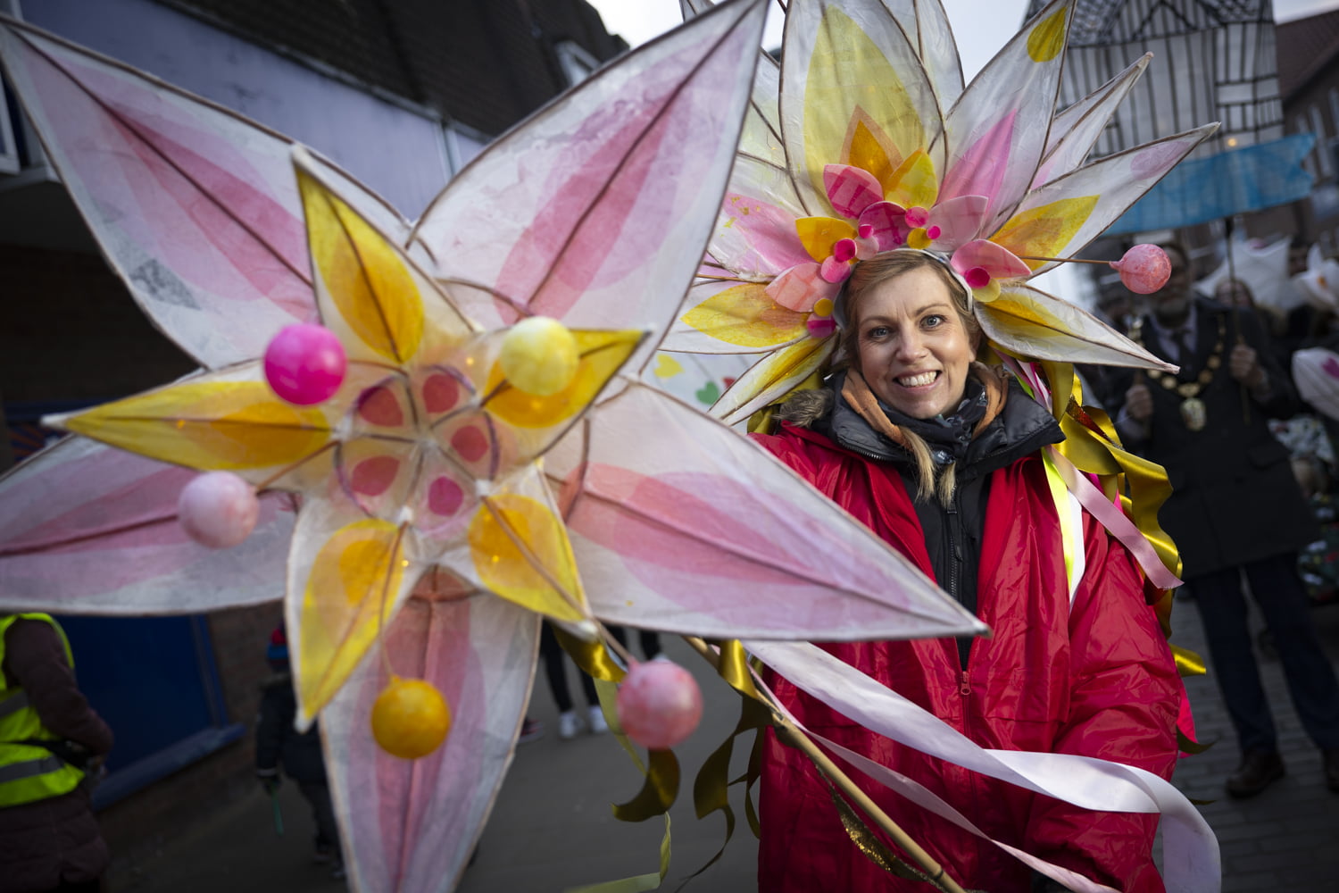 Wearing colourful handmade headdress and holding a large handmade flower lantern