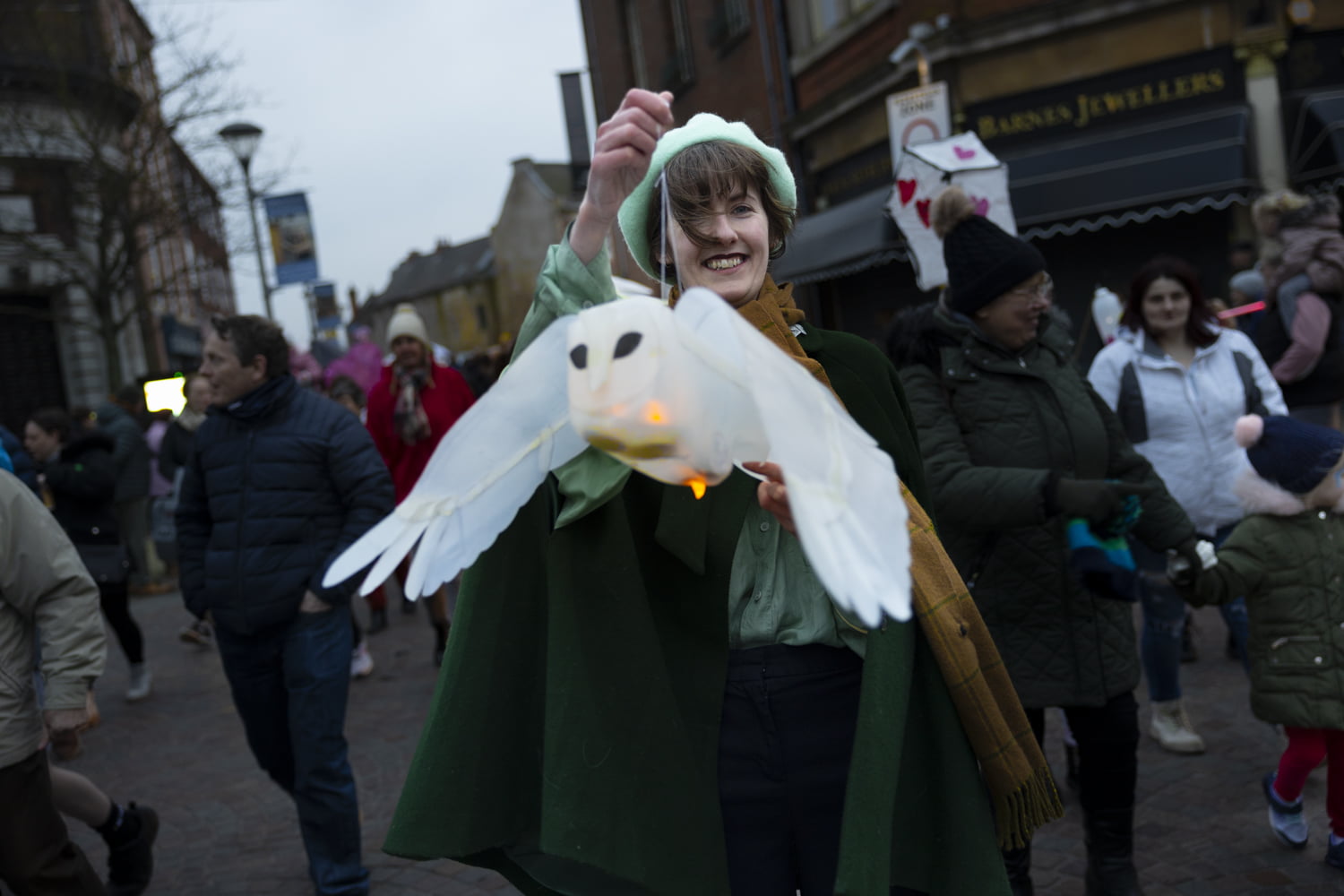 Woman holding up an owl lantern in the Illuminate 2024 parade.