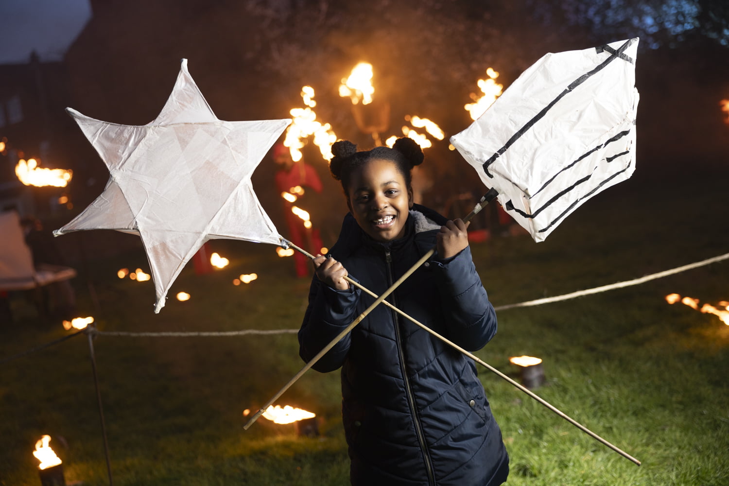 Girl holding 2 large lanterns in the Fire Garden at Illuminate 2024