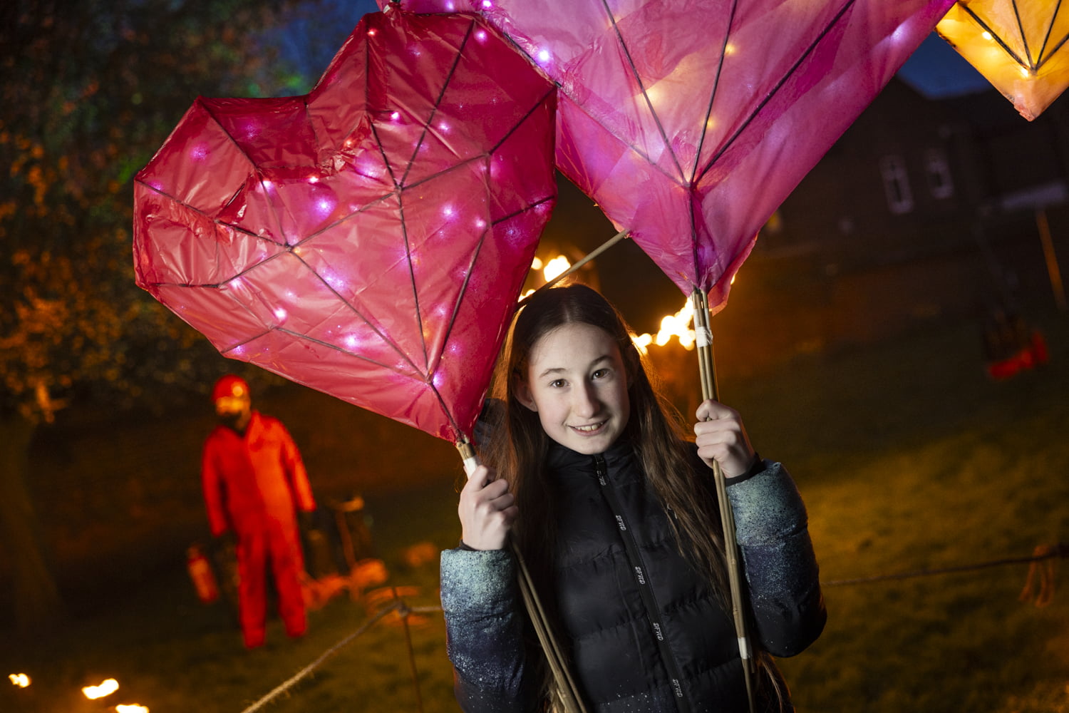 Girl holding 2 large heart lanterns in the Fire Garden at Illuminate 2024