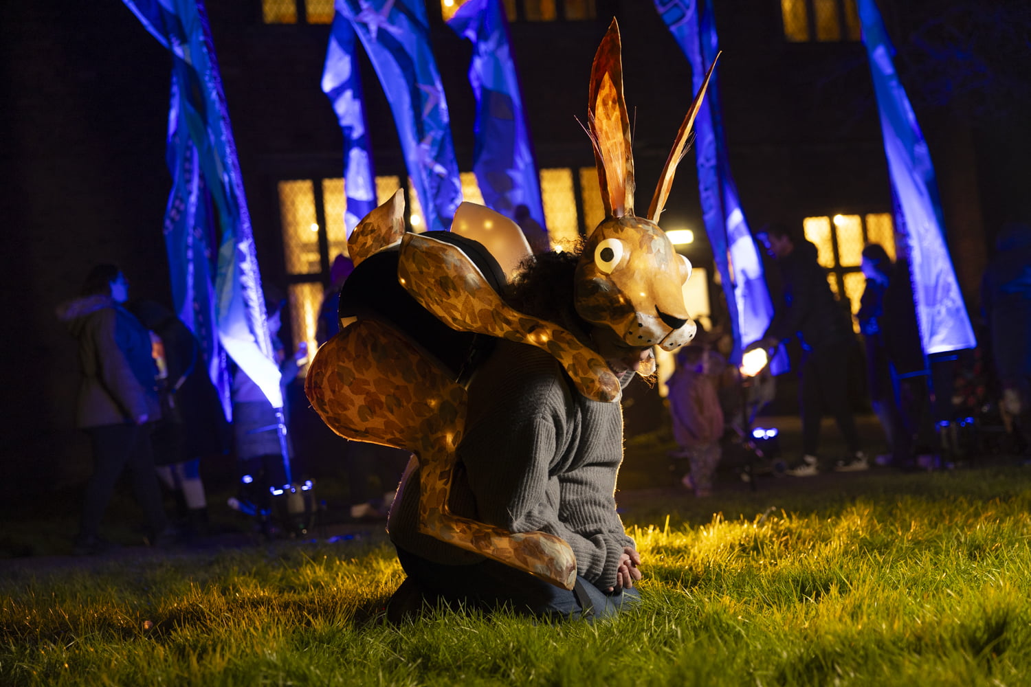 Woman wearing a hare lantern on her back and knelt down to look like a hare.