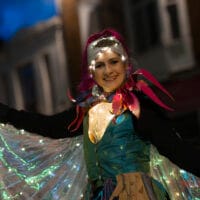 A performer wearing an illuminated cape at Illuminate 2025.