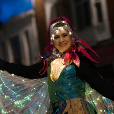 A performer wearing an illuminated cape at Illuminate 2025.