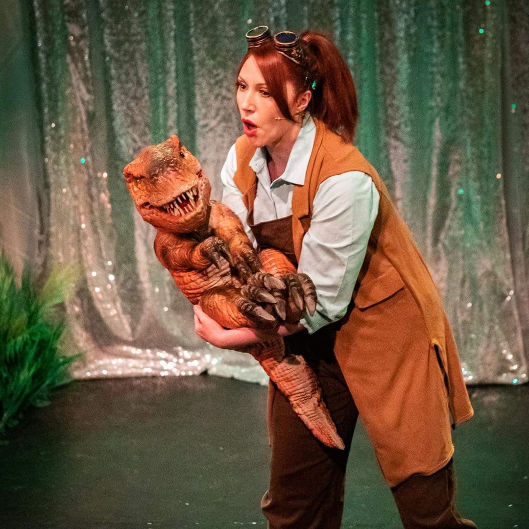 A woman holding a puppet dinosaur. The Dinosaur Timewarp comes this half term in Gainsborough at Trinity Arts Centre.